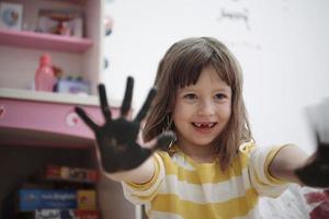 schattig weinig meisje Bij huis schilderij met handen foto