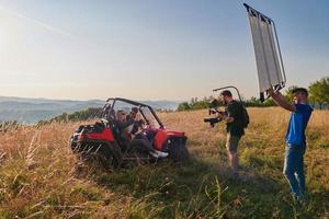 cameraman opname een jong paar genieten van een buggy auto rijden omhoog een berg foto