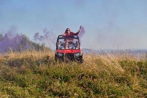 opgewonden mensen hebben pret genieten van mooi zonnig dag Holding kleurrijk fakkels terwijl het rijden een uit weg buggy auto foto