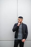 portret van elegant Arabisch baard Mens slijtage grijs coltrui en zwart jas. Arabisch model- vent tegen staal muur. foto