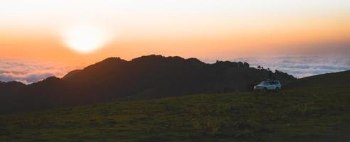 tour groep staan door 4wd voertuig Aan beroemd bakhmaro zonsondergang gezichtspunt kijk maar zonsondergang over- wolken in Georgië foto