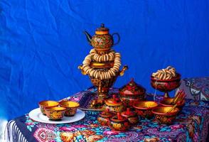 Aan de tafel Aan een kleurrijk tafelkleed is een traditioneel Russisch samovar. Russisch nationaal thee ceremonie foto