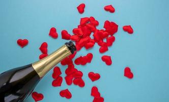 een Open fles van Champagne en rood harten Aan een blauw achtergrond. vakantie concept, nieuw jaar, Valentijnsdag dag, maart 8 foto