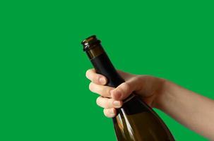 een vrouw hand- Holding een Open fles van Champagne Aan een groen achtergrond.vakantie concept foto