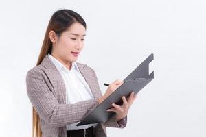 Aziatisch werken vrouw in formeel pak met wit overhemd is opent document het dossier of klembord naar controleren gegevens. foto