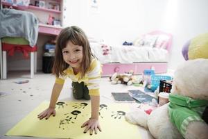 schattig weinig meisje Bij huis schilderij met handen foto