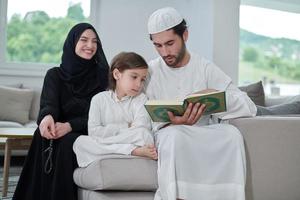 jong moslim familie lezing koran gedurende Ramadan foto