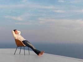 ontspannen jong Mens Bij huis Aan balkon foto