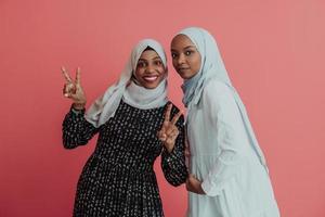 portret van twee jong modern moslim afro schoonheid vervelend traditioneel Islamitisch kleren Aan roze achtergrond foto