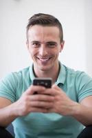 jonge man die thuis een mobiele telefoon gebruikt foto