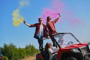 opgewonden mensen hebben pret genieten van mooi zonnig dag Holding kleurrijk fakkels terwijl het rijden een uit weg buggy auto foto