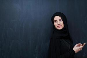 jong moslim zakenvrouw in traditioneel kleren of abaya gebruik makend van smartphone foto