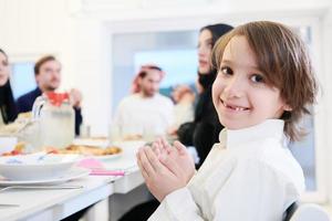 weinig moslim jongen bidden met familie voordat iftar avondeten foto