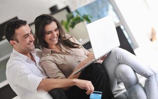 blij paar kom tot rust en werk Aan laptop computer Bij modern huis foto