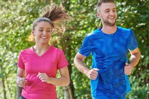 paar genieten van in een gezond levensstijl terwijl jogging Aan een land weg foto