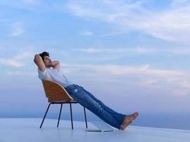 ontspannen jong Mens Bij huis Aan balkon foto