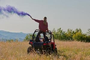 opgewonden mensen hebben pret genieten van mooi zonnig dag Holding kleurrijk fakkels terwijl het rijden een uit weg buggy auto foto