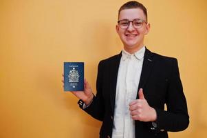 jong knap Mens Holding Canada paspoort ID kaart over- geel achtergrond, gelukkig en tonen duim omhoog. reizen naar Amerika landen. foto