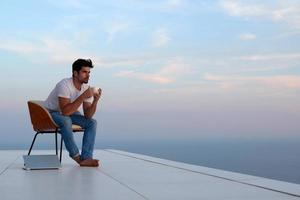 ontspannen jong Mens Bij huis Aan balkon foto