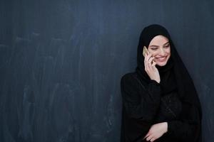 jong moslim zakenvrouw in traditioneel kleren of abaya gebruik makend van smartphone foto