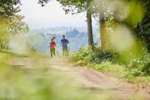 paar genieten van in een gezond levensstijl terwijl jogging Aan een land weg foto