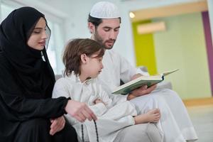 jong moslim familie lezing koran gedurende Ramadan foto