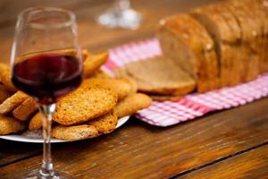 glas van rood wijn en geroosterd brood Aan houten tafel foto