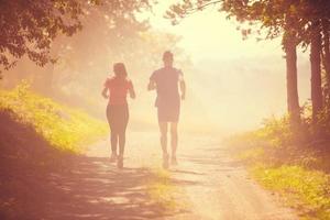 jong paar jogging Aan zonnig dag Bij natuur foto