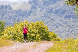 jong vrouw jogging Aan zonnig dag Bij natuur foto