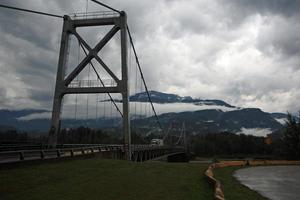 een oplegger vrachtauto Aan een brug over- een rivier- door een berg bereik. foto