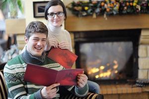 jong romantisch paar zittend en ontspannende in voorkant van haard Bij huis foto