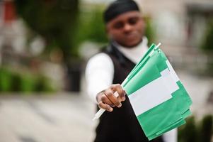 jong Afrikaanse Amerikaans Mens houden Nigeriaans vlaggen in handen. foto