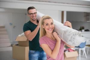 paar draag- een tapijt in beweging in naar nieuw huis foto