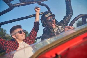 twee jong gelukkig opgewonden mannen genieten van mooi zonnig dag terwijl het rijden een uit weg buggy auto foto