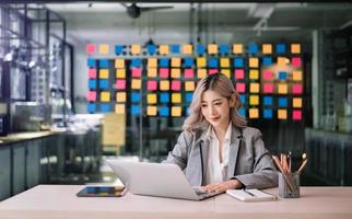 zelfverzekerd bedrijf deskundige aantrekkelijk glimlachen jong vrouw Holding digitaal tablet Aan bureau in creatief kantoor. foto