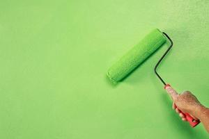 rol borstel schilderen, arbeider schilderij Aan oppervlakte muur schilderij appartement, renoveren met groen kleur verf. foto