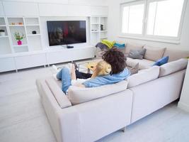 jong koppel op de bank televisie kijken foto