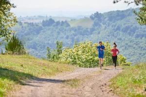 paar genieten van in een gezond levensstijl terwijl jogging Aan een land weg foto