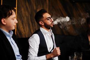 groep van knap retro goed gekleed Mens gangsters besteden tijd Bij club, roken hookah. multi-etnisch mannetje bachelor opleiding maffia partij in restaurant. foto