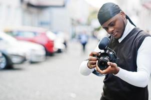 jong professioneel Afrikaanse Amerikaans videograaf Holding professioneel camera met pro apparatuur. afro cameraman vervelend zwart Duraq maken een videos. foto