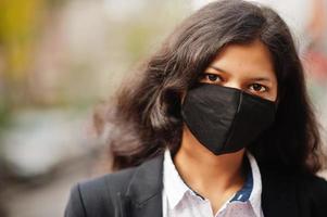 prachtig Indisch vrouw slijtage formeel en zwart gezicht masker, poseren Bij straat gedurende covid pandemie. foto