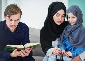 jong moslim familie lezing koran gedurende Ramadan foto