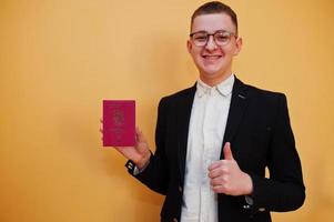jong knap Mens Holding een land paspoort ID kaart over- geel achtergrond, gelukkig en tonen duim omhoog. reizen naar Europa land concept. foto
