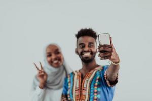 een jong Afrikaanse paar nemen een selfie Aan hun smartphone, mijn schoenen in traditioneel Soedan kleren. selectief focus. foto