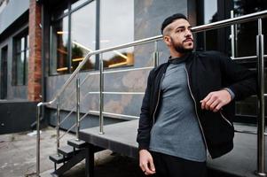 portret van elegant Arabisch baard Mens slijtage grijs coltrui en zwart jas. Arabisch model- jongen. foto