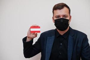 Europese Mens slijtage zwart formeel en beschermen gezicht masker, houden Oostenrijk vlag kaart geïsoleerd Aan wit achtergrond. Europa coronavirus covid land concept. foto