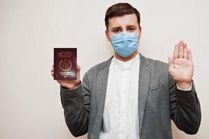 Europese Mens in formeel slijtage en gezicht masker, tonen noordelijk Cyprus paspoort met hou op teken hand. coronavirus vergrendeling in Europa land concept. foto