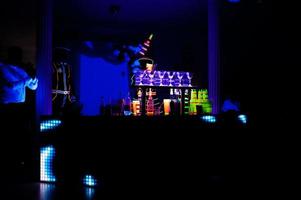 professioneel barman en LED licht show. silhouet van modern barman beven drinken Bij nacht cocktail bar. foto