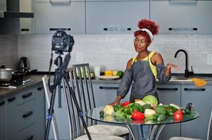 Afrikaanse Amerikaans vrouw filmen haar blog uitzending over gezond voedsel Bij huis keuken. foto