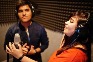 jong Aziatisch duet zangers met microfoon opname lied in Vermelding muziek- studio. foto